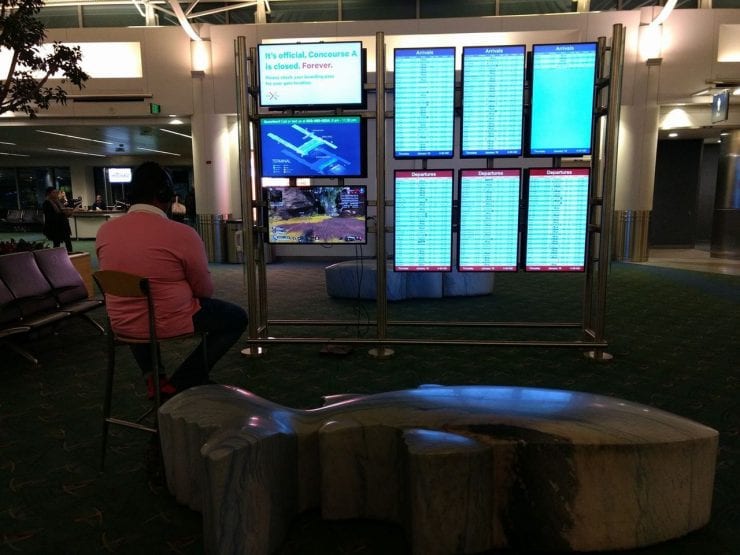 Viajero conecta la PlayStation 4 a un monitor de información en el Aeropuerto de Portland para jugar al Apex Legends